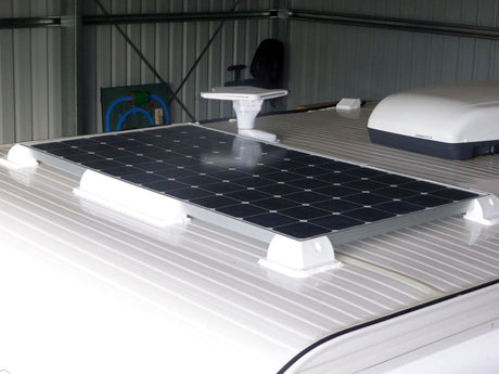 Rigid framed solar panel on white corner brackets on an RV roof