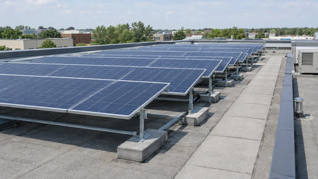 A solar module array on a commercial flat roof with the building and service walkways in the distance, showing a commercial installation setting.
