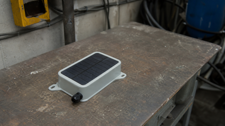 Compact integrated mini solar device with flush solar window and mounting ears in an industrial workspace