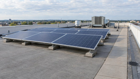 Rows of solar panels on a commercial flat roof with walkways, drains and rooftop equipment, showing what a site layout assessment covers.