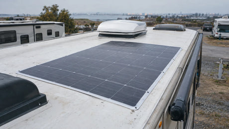 One finished flexible photovoltaic module laid flat for a dry fit review on a parked RV roof, roof vent and clearance visible, no forced bending, bonding or claim of approved installation.