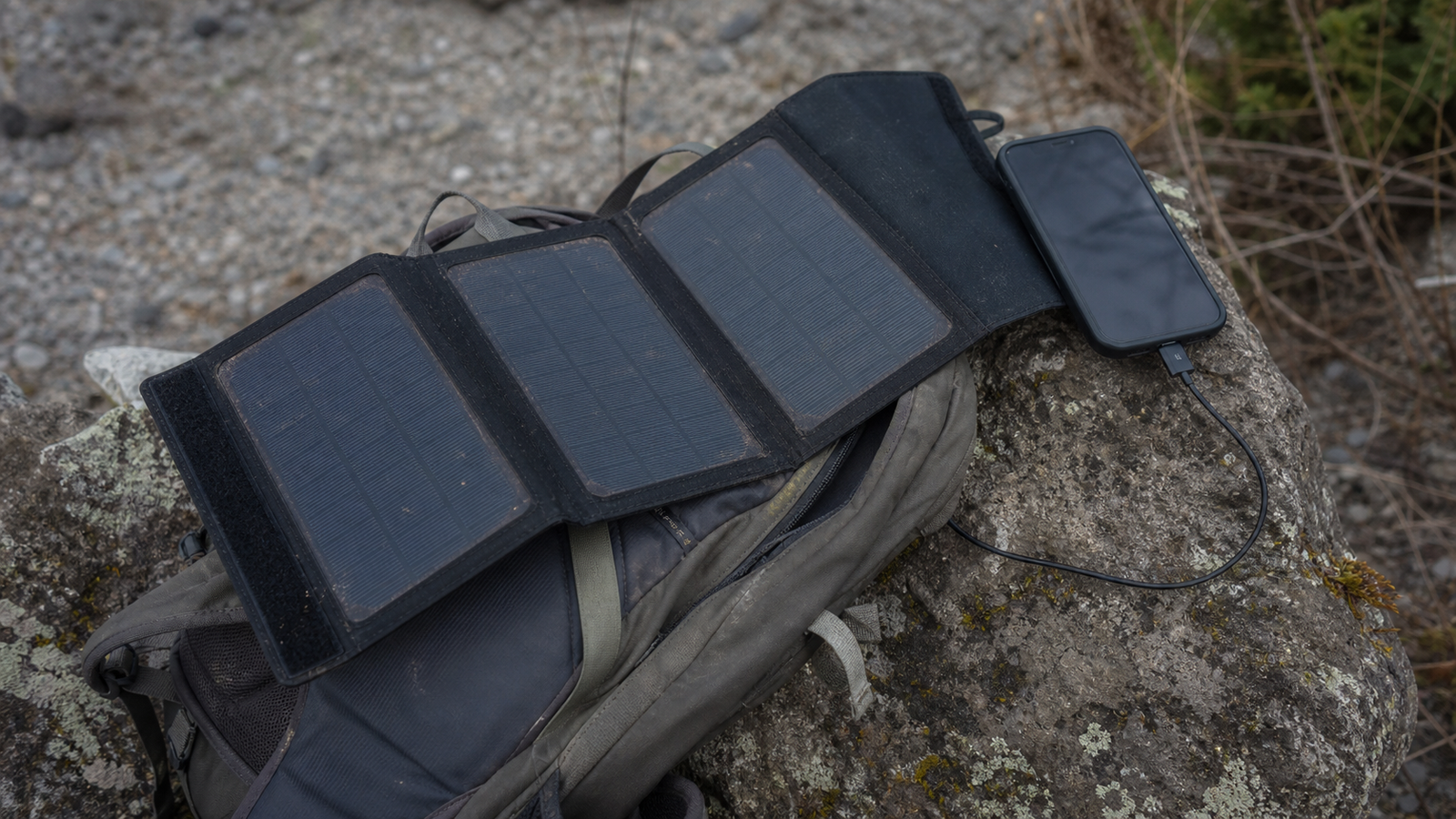 Foldable solar charger unfolded on a backpack in an outdoor setting