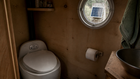 Nature's Head composting toilet solar fan setup in off-grid cabin bathroom