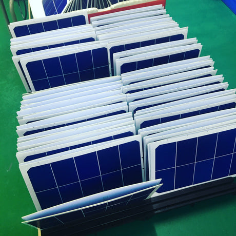 Batch of small solar panels standing in production racks on a factory floor before inspection