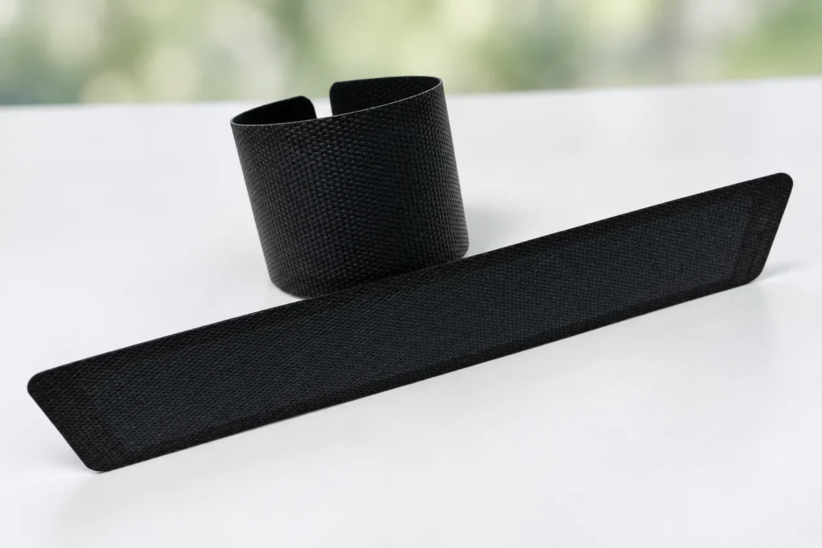AI-edited user photograph: one textured flexible strip rolled and a second strip laid flat