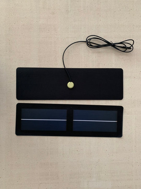 Slim black solar panel shown front and back, with a lead and plug for mounting away from the light it charges