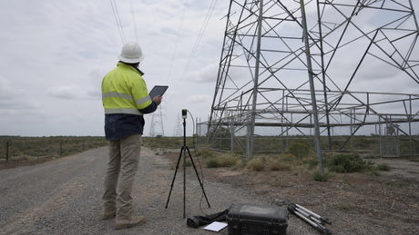 A site survey at the base of a transmission tower along a line corridor.
