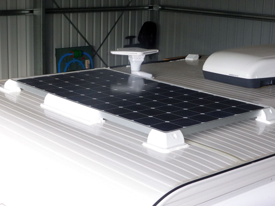 Rigid solar panel mounted on RV roof with white bracket mounts
