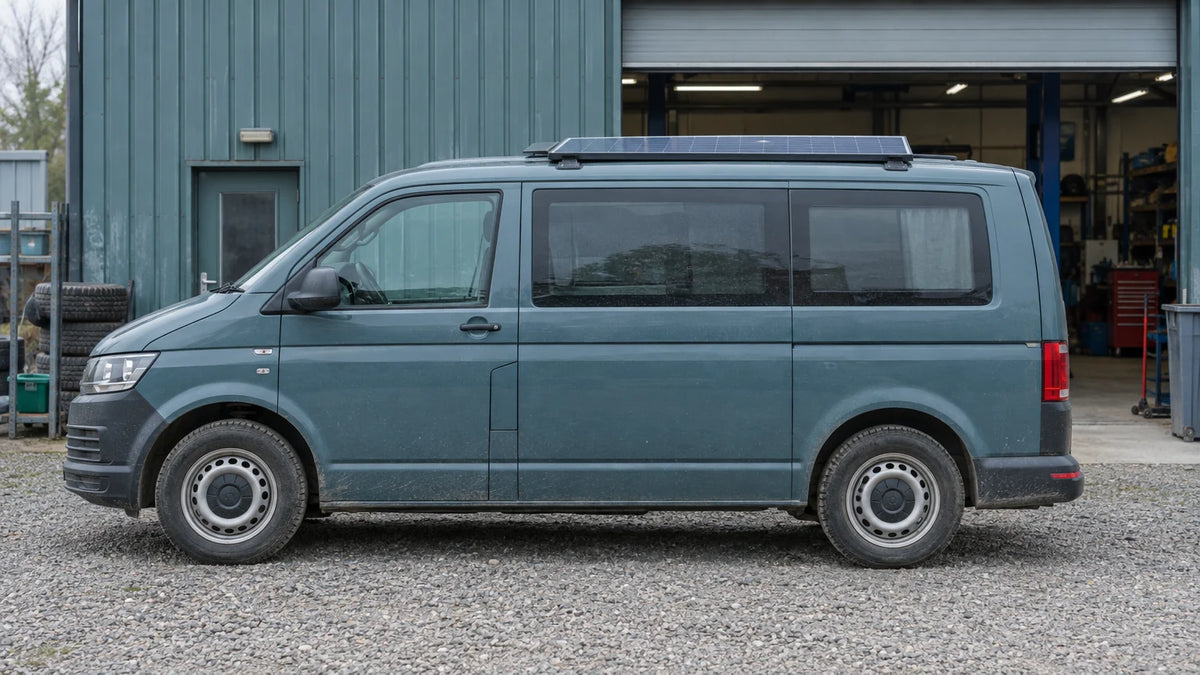 An unbranded camper van with a roof solar module is parked at a practical service site, illustrating an upgrade project with existing equipment retained.