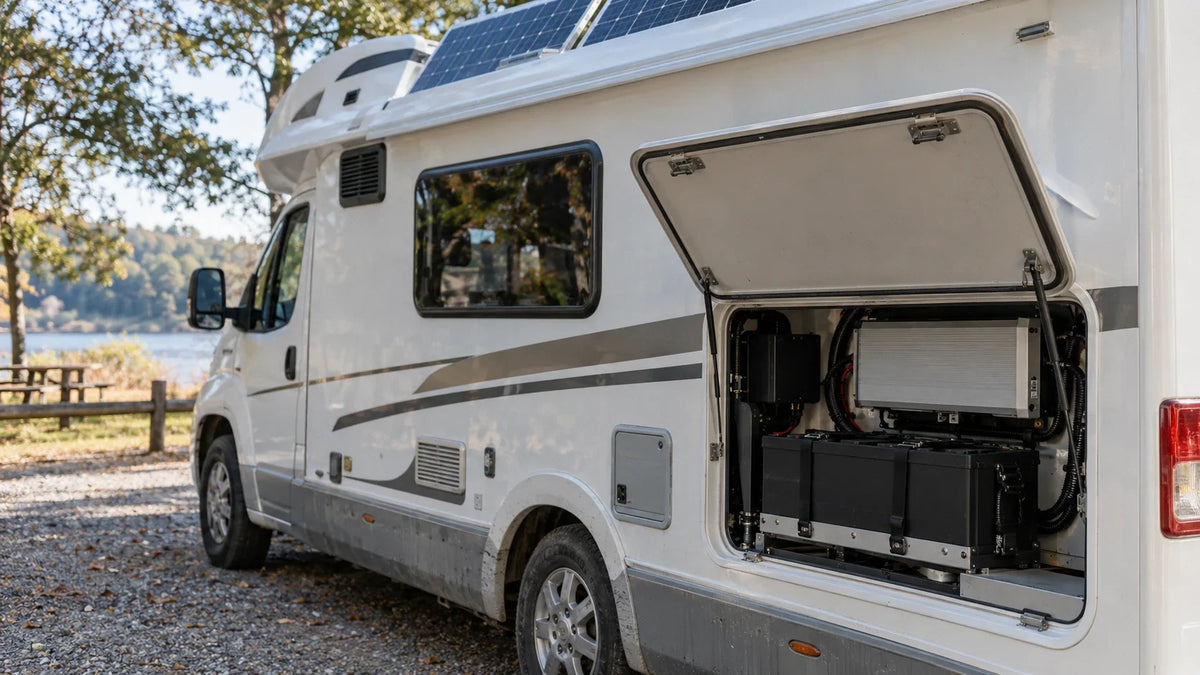 An RV solar array and open service compartment show the protected battery and closed inverter of a complete kit.