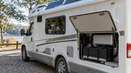 An RV solar array and open service compartment show the protected battery and closed inverter of a complete kit.