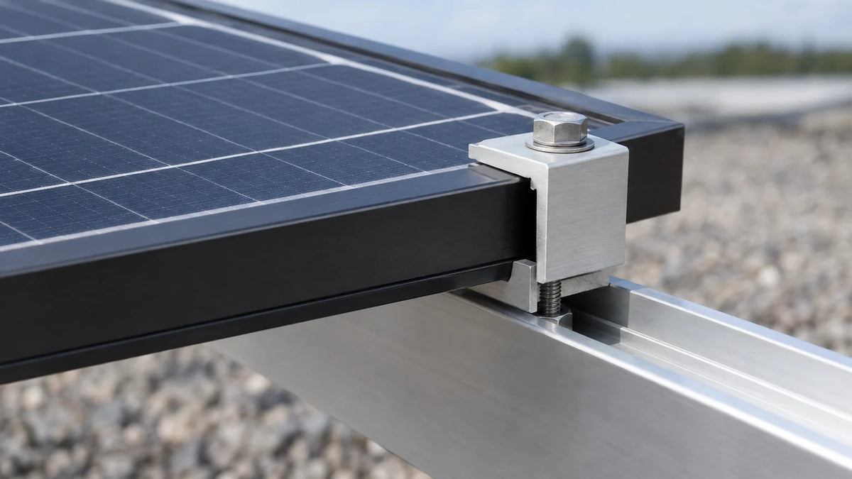 The outer frame of a solar array fixed to an aluminum rail with an end clamp, close-up separating the clamp, module frame and rail.