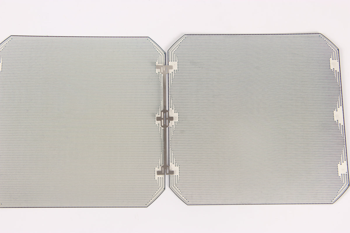 Rear side of two back-contact solar cells joined by a stamped metal interconnect, the joint that links cells into a string
