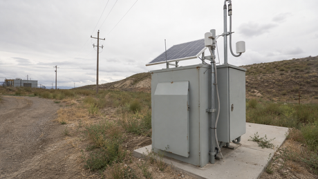 A modular solar power cabinet installed at a remote industrial telemetry site with solar panel and antenna feed-throughs.