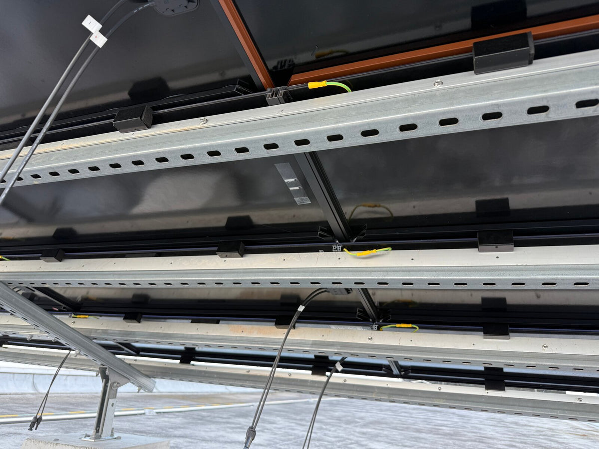 Underside view of a solar roof tile mounting rail with clips and wiring during installation