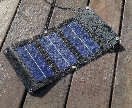 Waterproof mini solar charger with water droplets on wooden deck