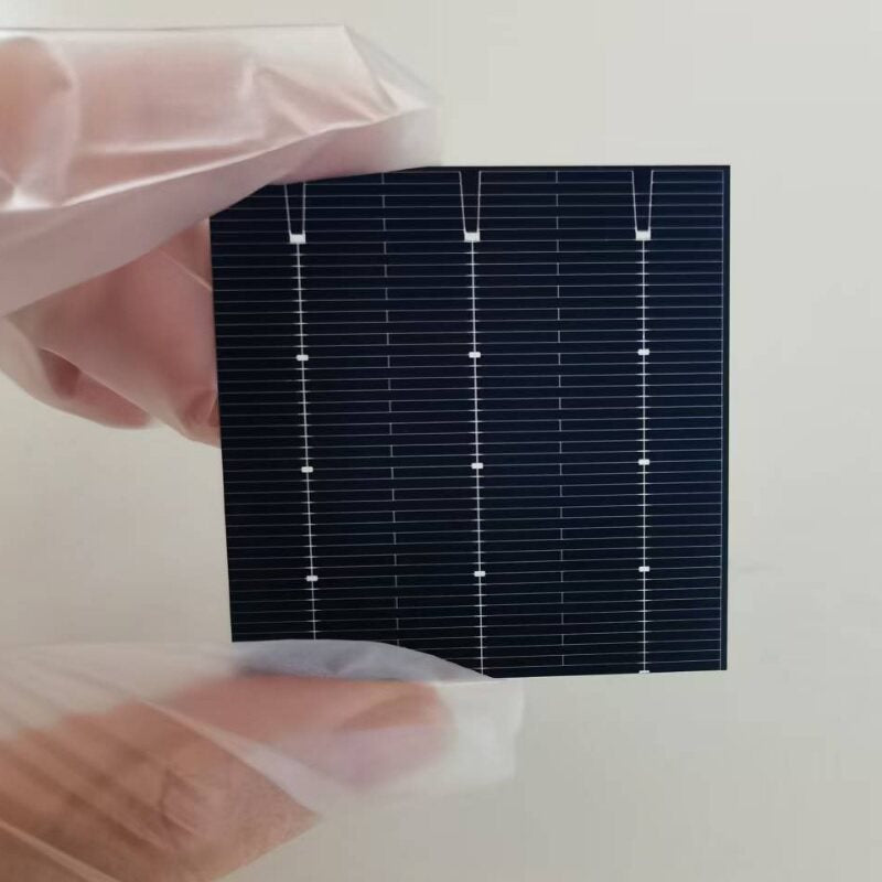 Gloved hands holding the front side of a 52mm bifacial PERC solar cell