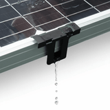 Black ABS drain clip mounted on a framed solar panel edge with water dripping through.