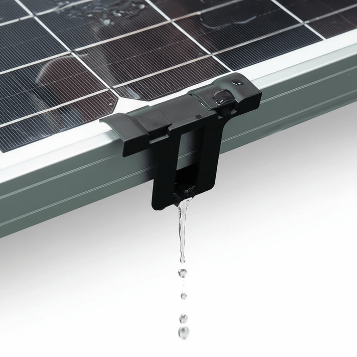 Black ABS drain clip mounted on a framed solar panel edge with water dripping through.