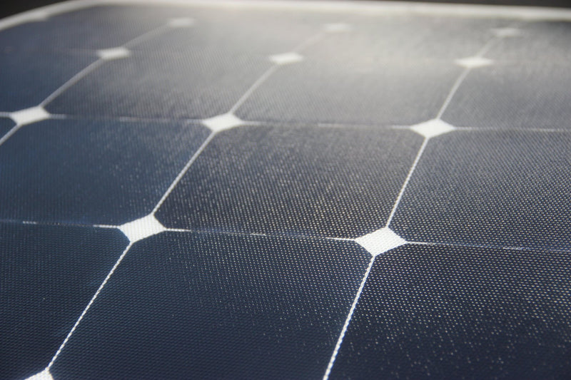A macro, low-angle view of an ETFE solar panel surface, highlighting the fine, dimpled texture of the cells and the white grid separating them.