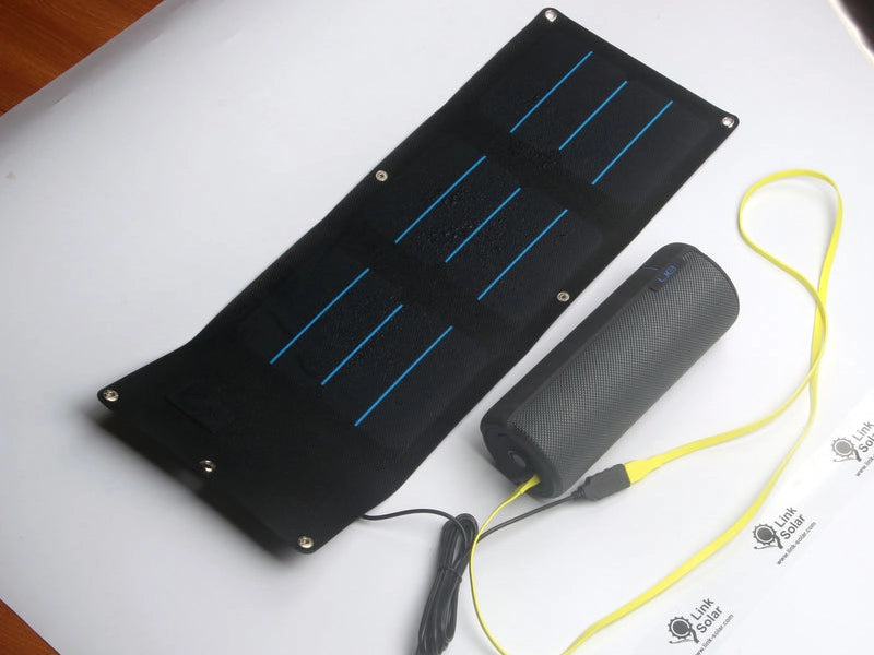 compact foldable solar charger powering portable Bluetooth speaker through USB connection