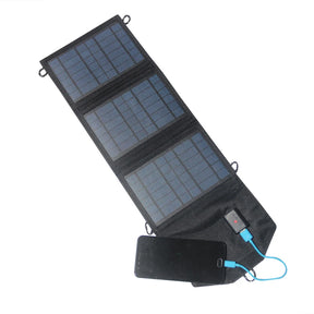 Three-section black foldable USB solar charger opened beside a phone