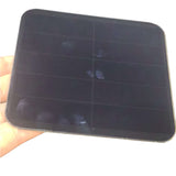 Handheld view of the 113×113 mm glass mini solar panel, front side visible.