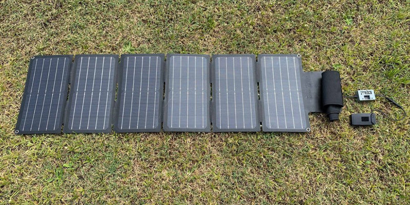 multiple panel foldable solar blanket deployed on grass for camping power supply