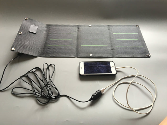 ultra thin foldable solar charger connected to smartphone during outdoor charging