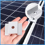 Silver solar panel mid clamp positioned between framed modules on a mounting rail