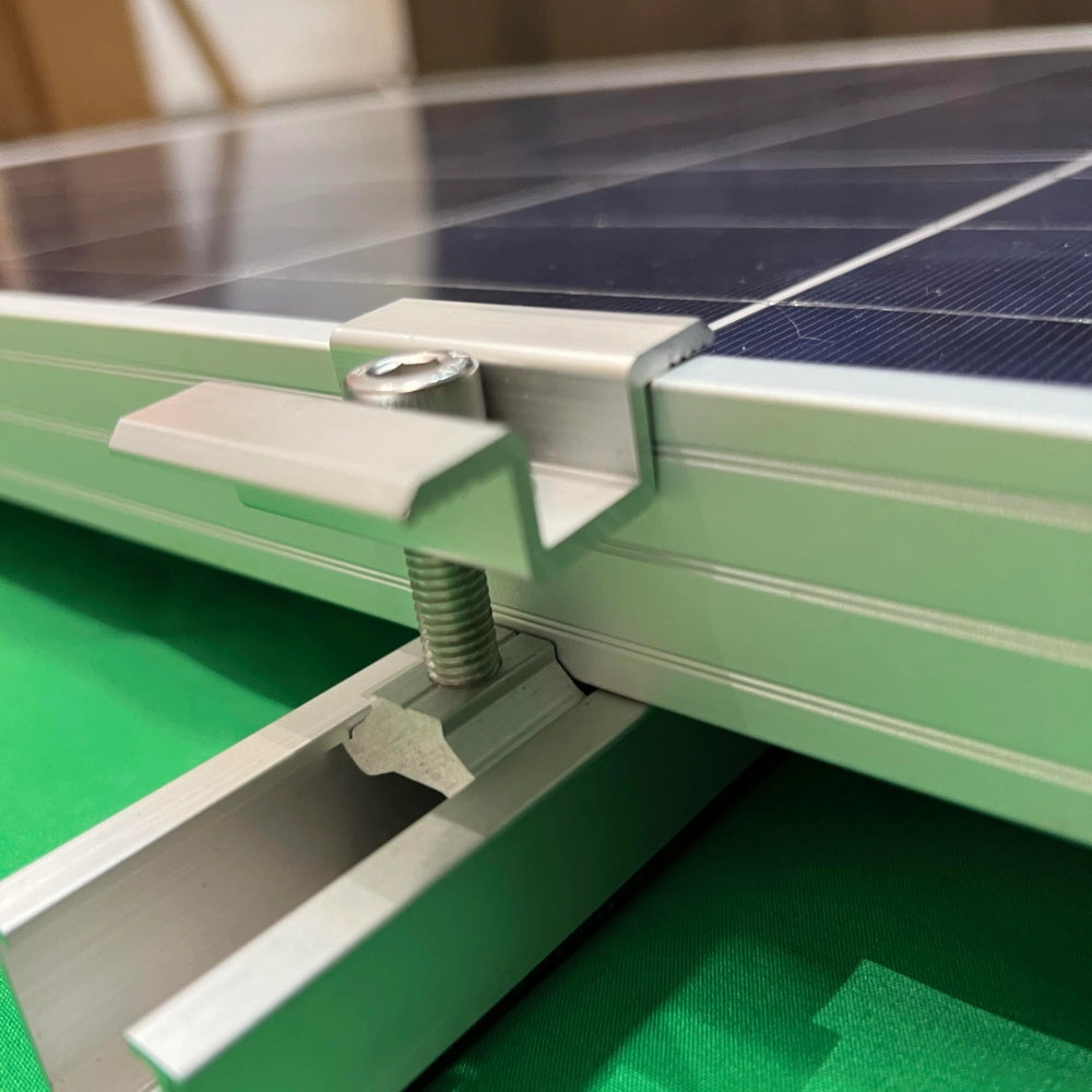 A close-up photograph of an aluminum mid clamp securely fastening two adjacent solar panels together on a mini mounting rail.