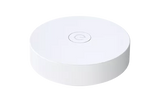 White round wireless gateway puck with a central ring symbol, top view.